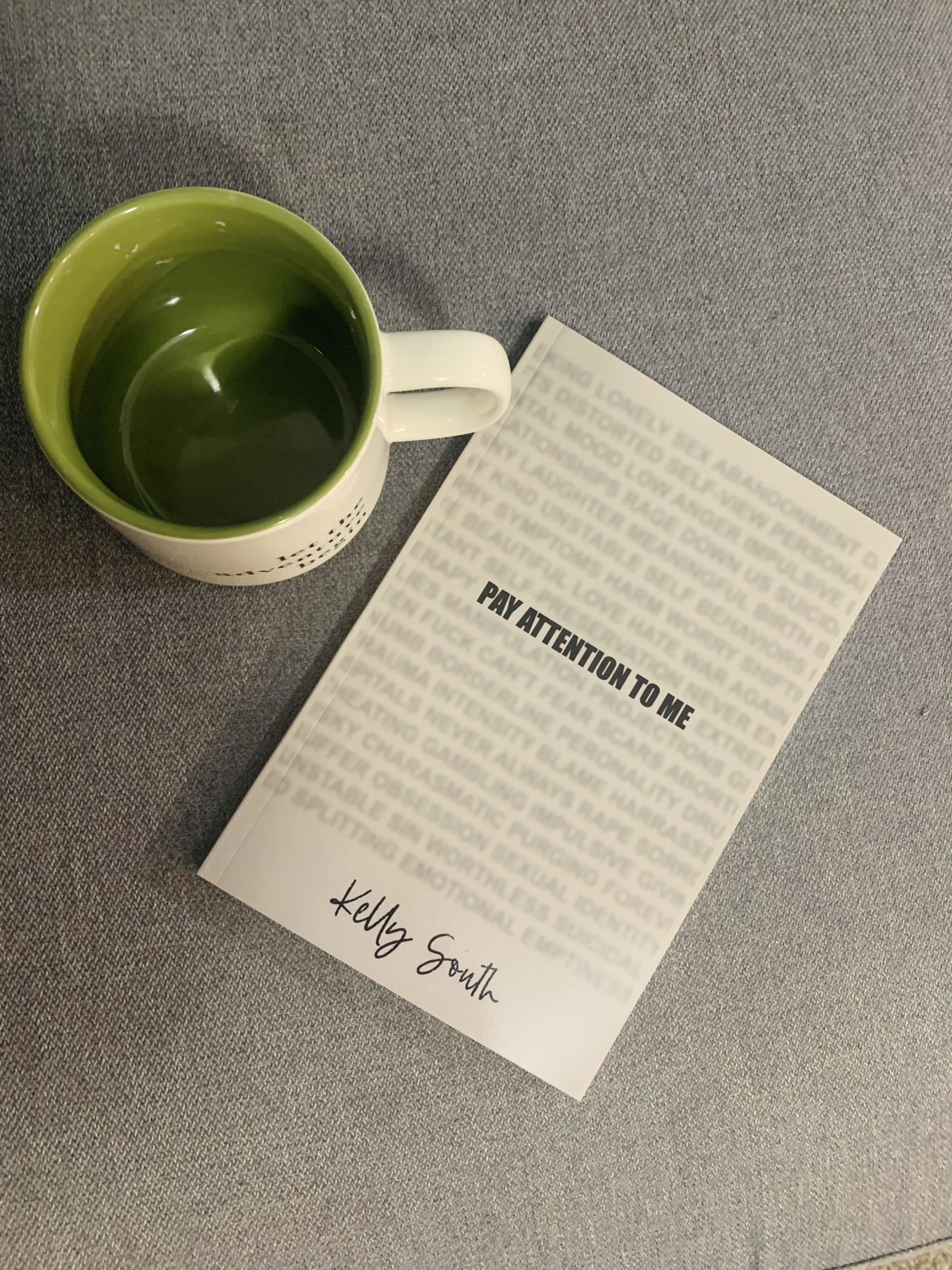 Photo of a book about BPD called Pay Attention to Me on a gray background next to a green & white mug